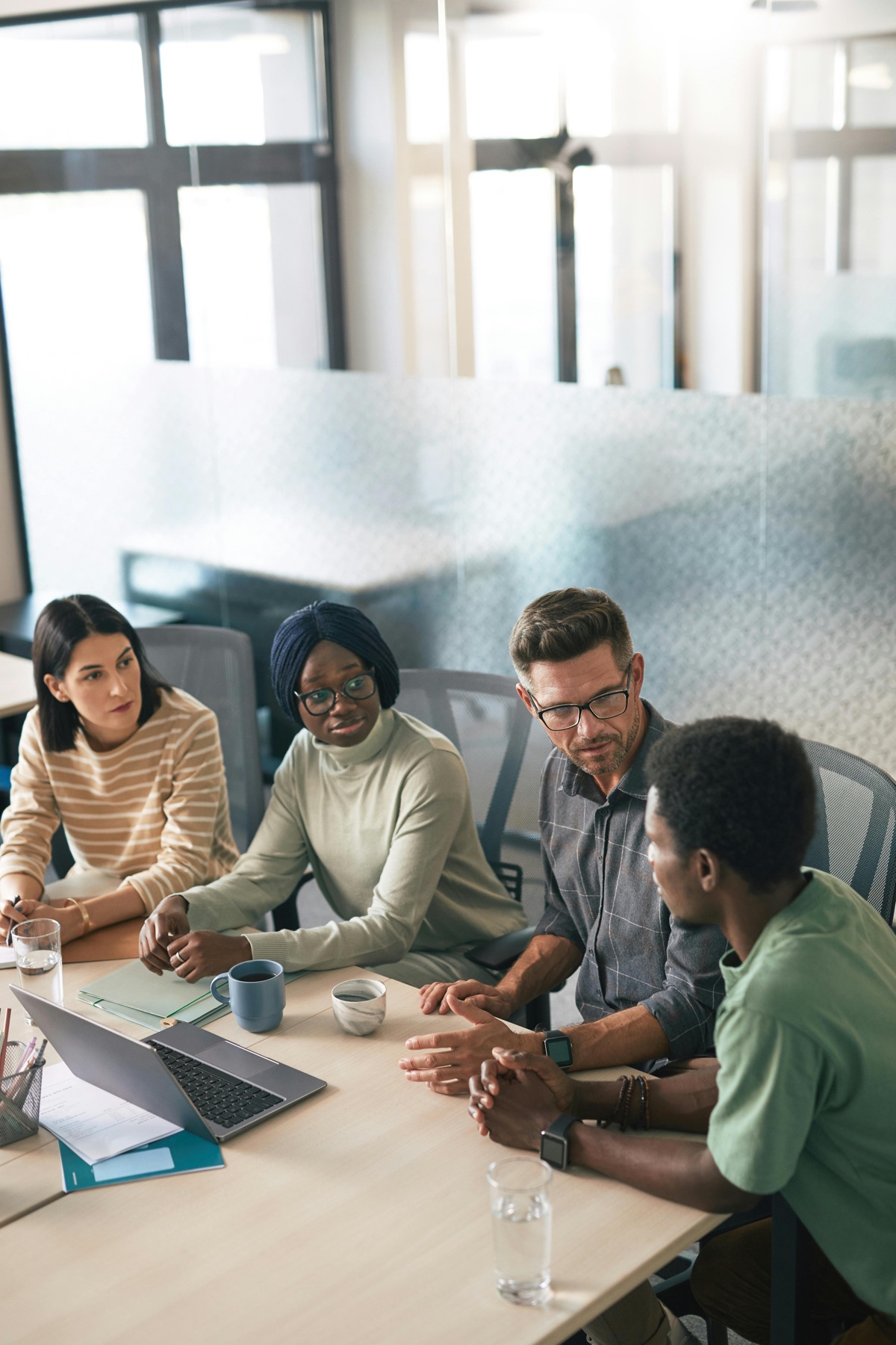 A diverse agency team sitting around a conference table reviewing a client security questionnaire on a laptop